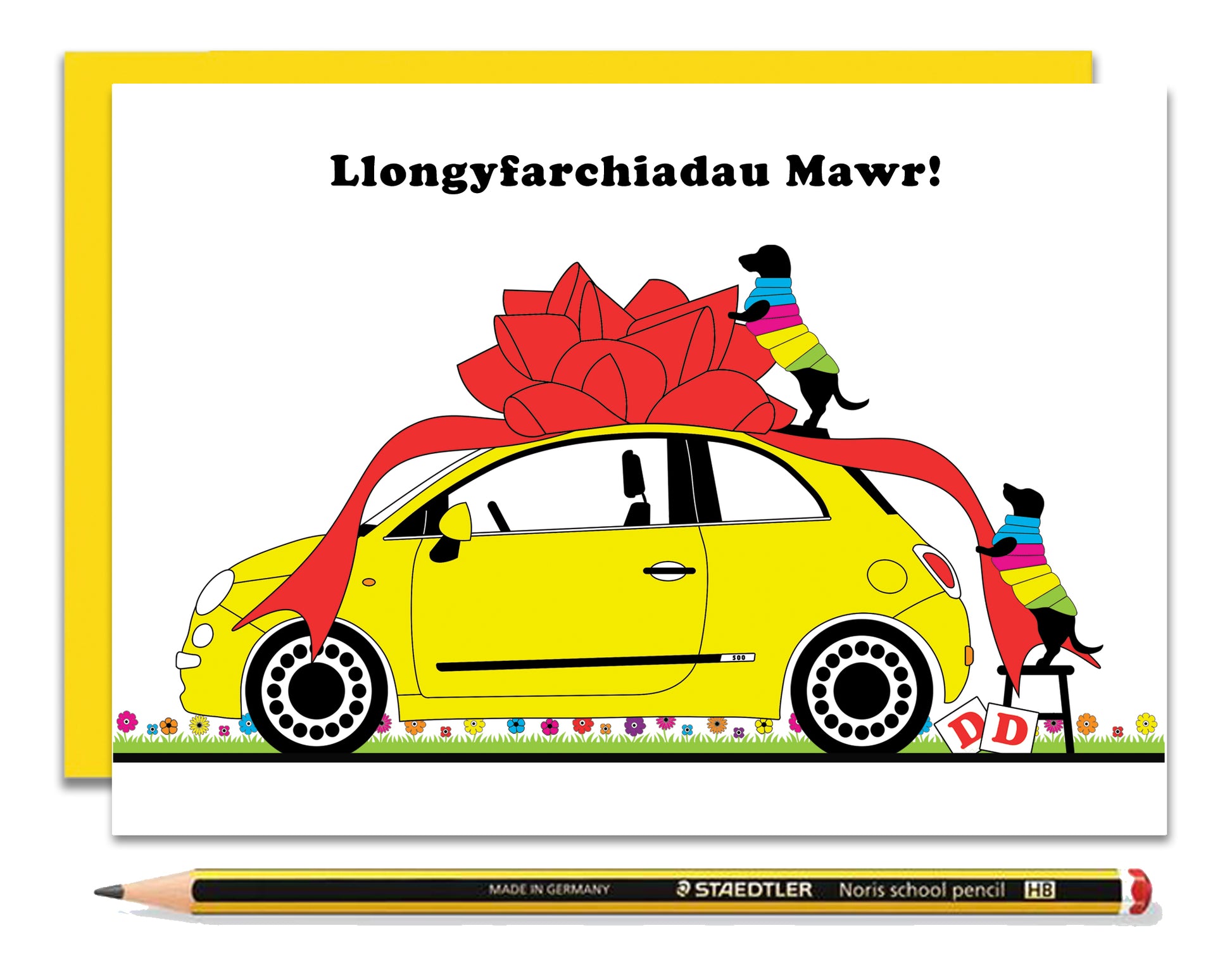 A Welsh driving test card featuring dachshunds, Mali & Penny.  This Welsh card shows them wrapping a lovely little yellow fiat in a big red bow to celebrate somebody passing a driving test.  Message reads - Many Congratulations.  Coupled with a bright, cheerful yellow envelope, with a pencil to show the scale of the card.